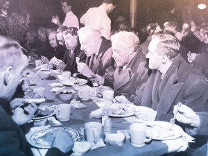 Photo d'hommes rassemblés à une table lors du repas de Noël de 1950.