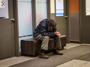 Photo of a man sitting on a bench at the Old Brewery Mission reception desk in the Webster Pavilion.