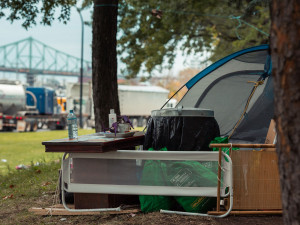 Une photo d'un campement de fortune près de la rue Notre-Dame à Montréal, avec le pont Jacques-Cartier en arrière-plan.