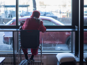Image capturée depuis l'intérieur de la halte-répit Café Mission Keurig, mettant en scène une femme se tenant devant les fenêtres de l'établissement, observant l'extérieur.